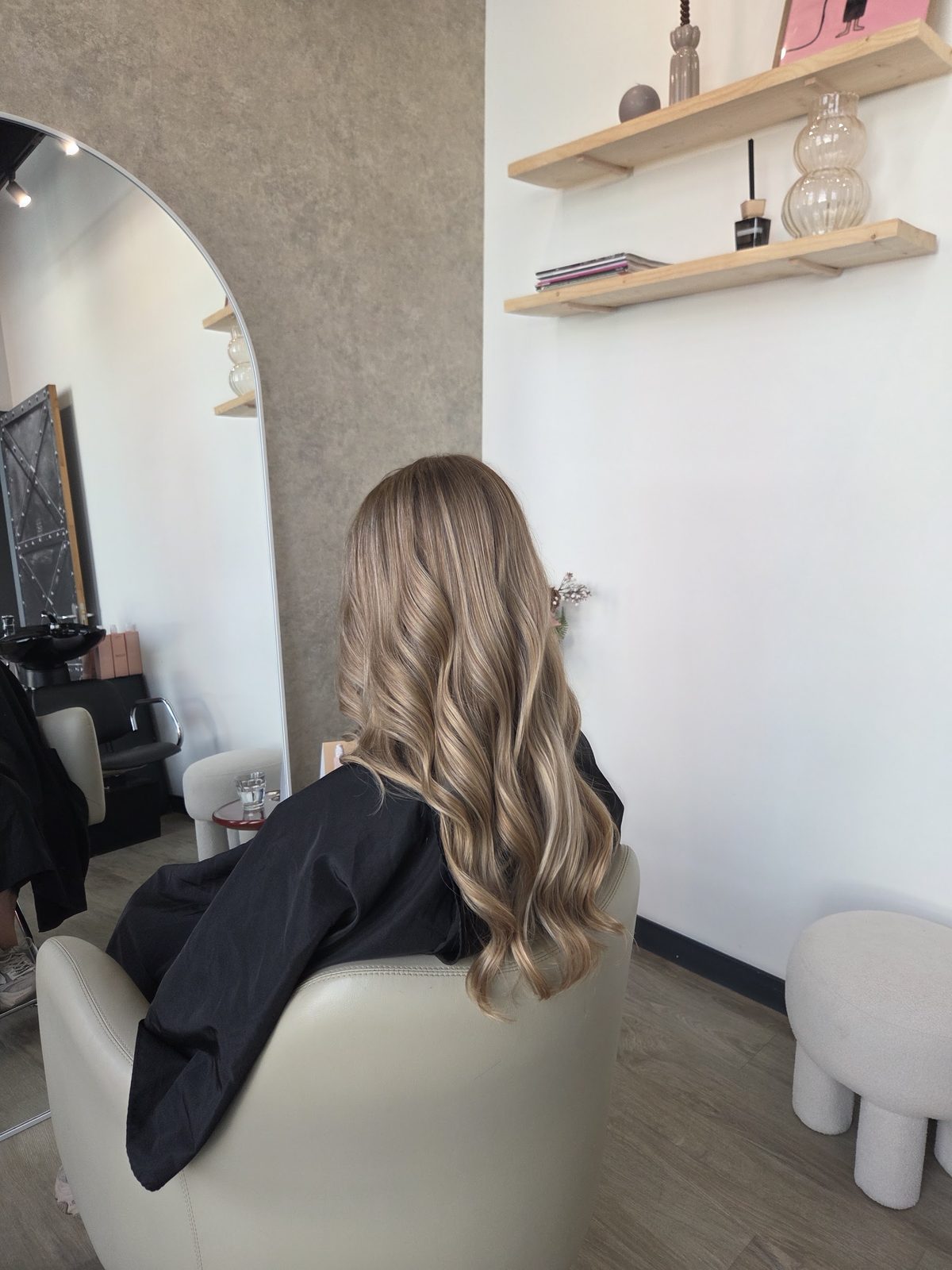 Een klant met blond haar in de stoel, met de houten wandplanken